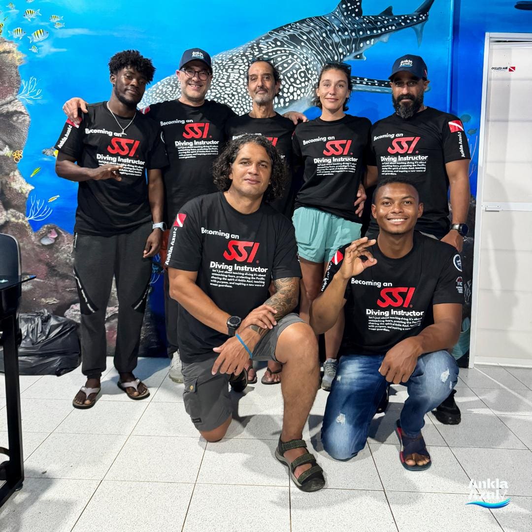 Group of diving students and instructors posing with SSI shirts in a classroom at Ankla Azul