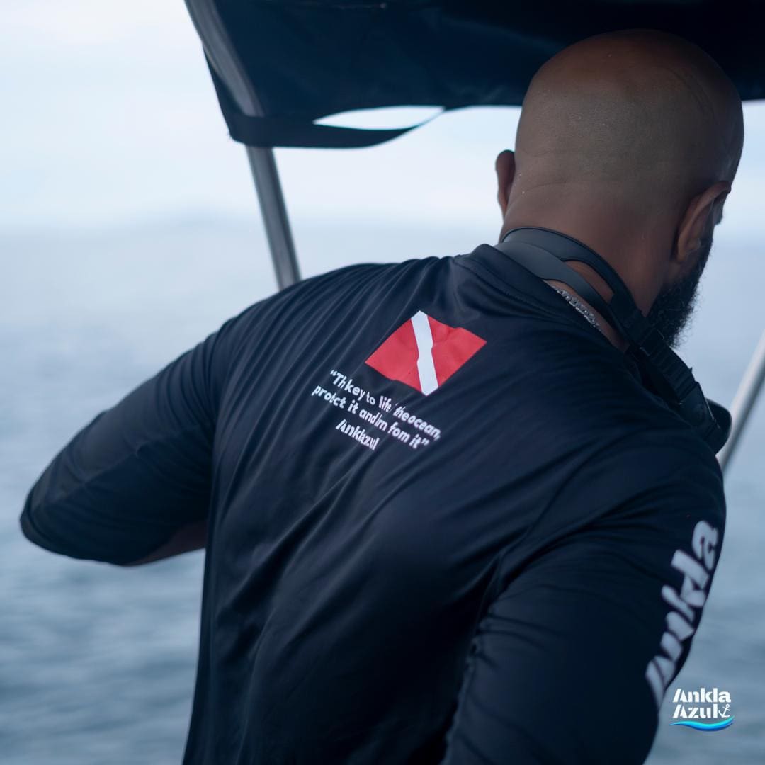 Back of a diver wearing an Ankla Azul rashguard with diver‑down flag on a boat