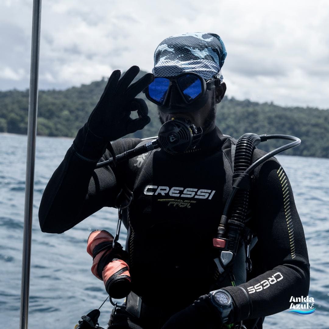 Scuba diver on a boat giving the OK sign before entering the water at Ankla Azul.