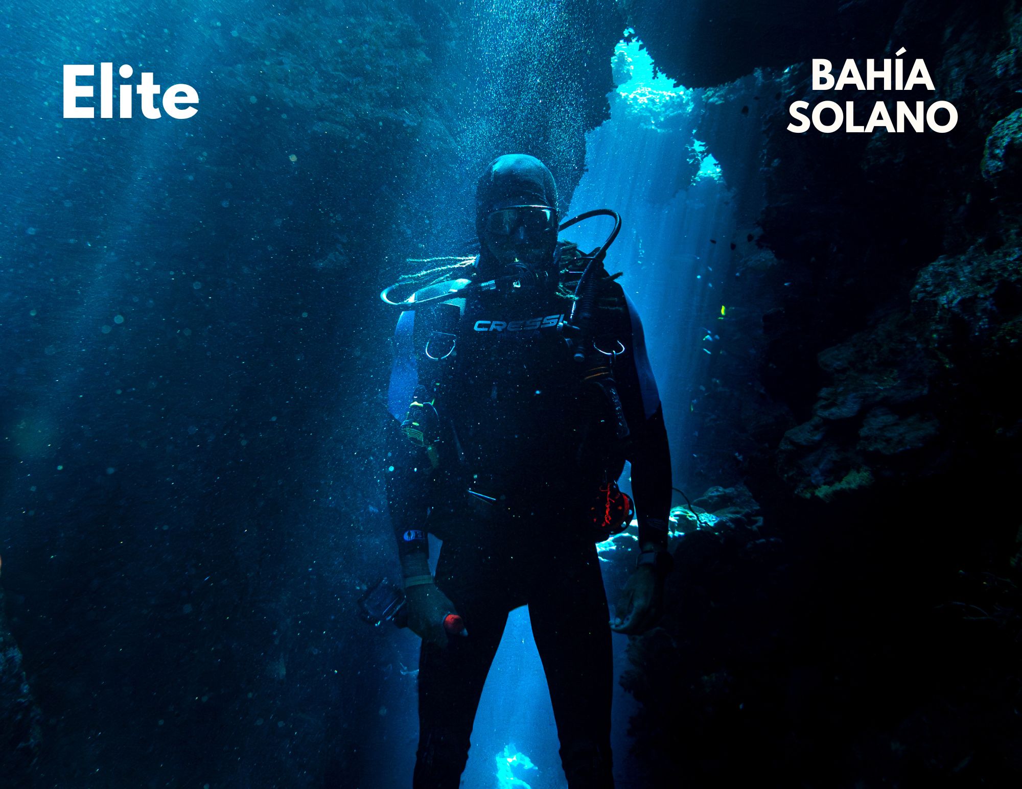 A dramatic silhouette of a diver standing in a dark underwater cavern with light streaming from above, with the text "Elite" overlaid.